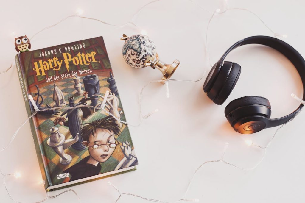 pexels-photo-1005012 Minimalist setup with Harry Potter book, headphones, and string lights for a cozy reading experience.